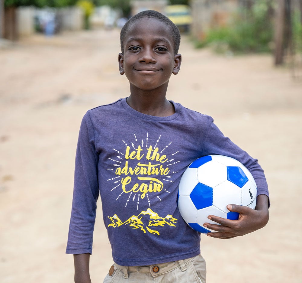 David smiling and holding a football after cleft surgery