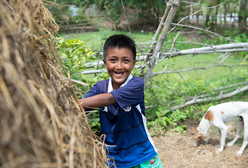 Sokim playing in the hay outside his house