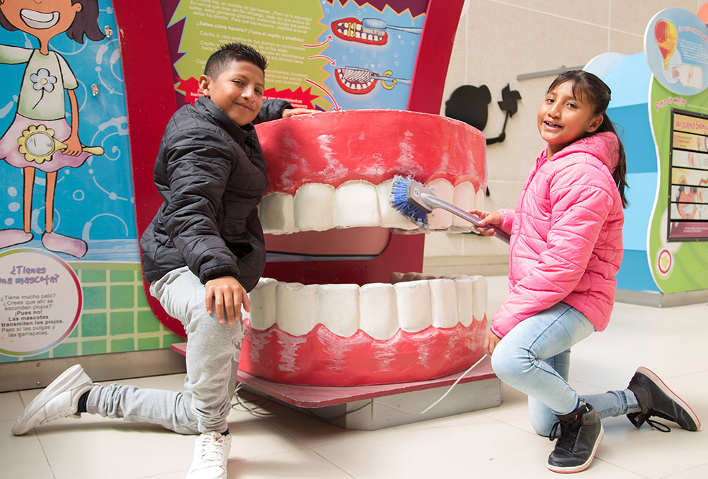 Alex and Kendra demonstrate tooth brushing technique on a giant mouth