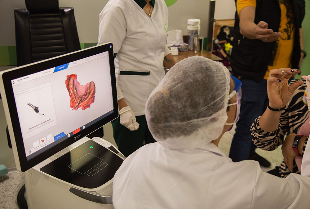 A technician at FISULAB reviews a 3D scan from Primescan with a patient's mother