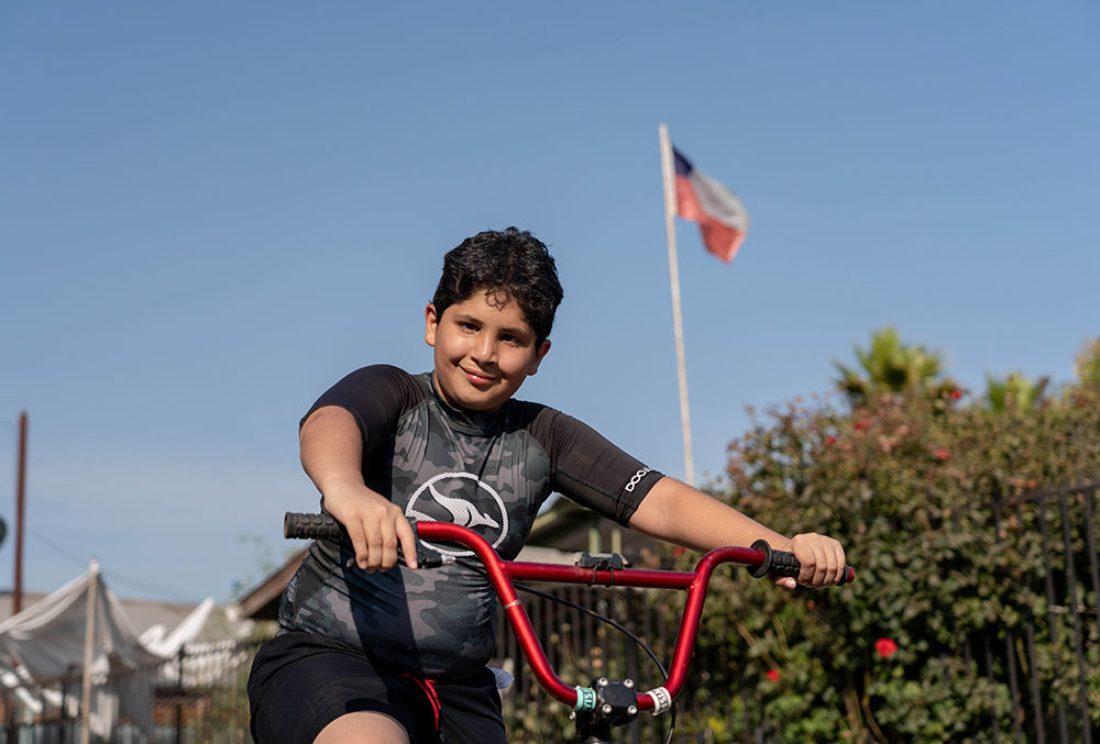 Juan riding his bike with a Chilean flag in the background