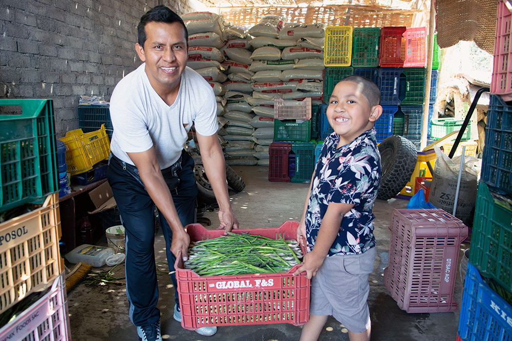 Ramses helping Luis carry a box of vegetables