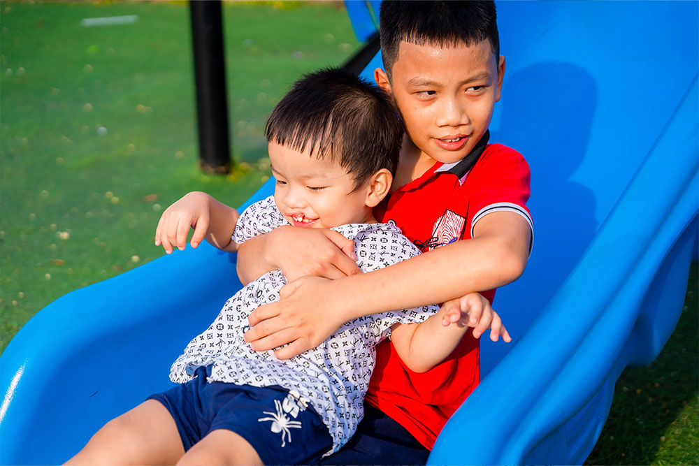 Quy holds Dat as they go down a slide together