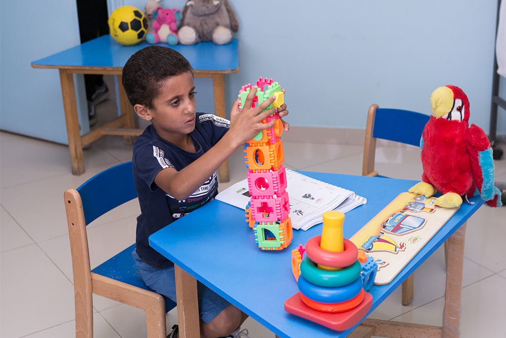 Fares building a block tower during speech therapy