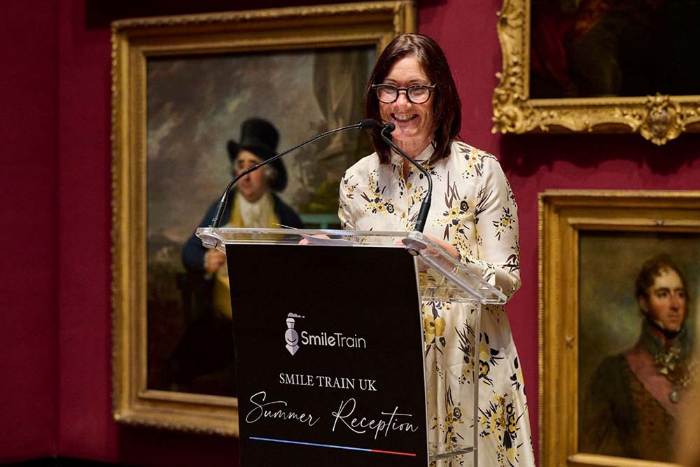 Susannah Schaefer standing at a podium in front of paintings