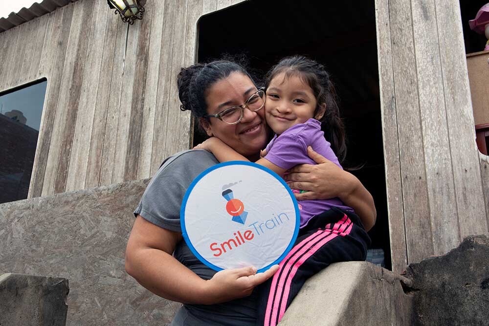 Itzayana and Xiomara holding a Smile Train logo