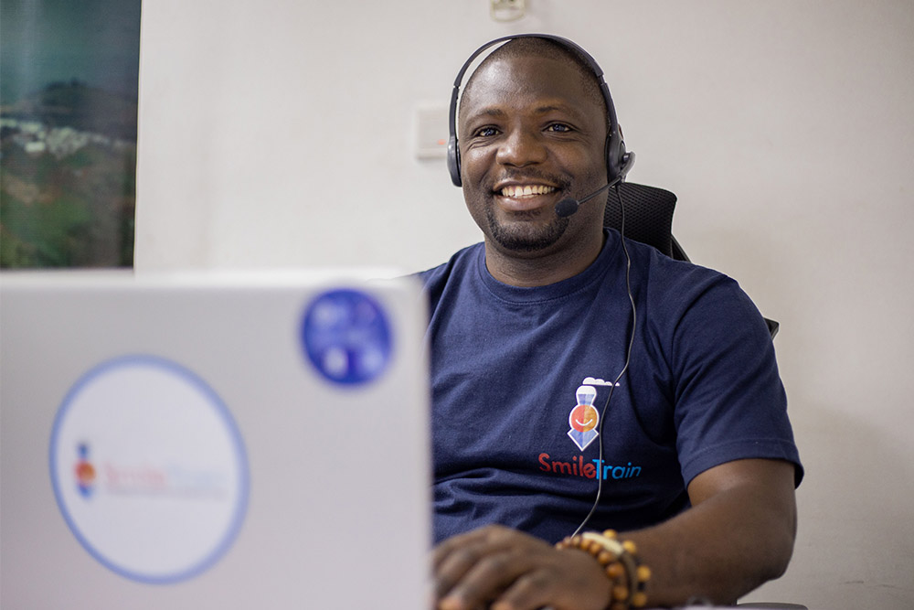 Paul Lobi smiling and helping patients on his computer through the helpline