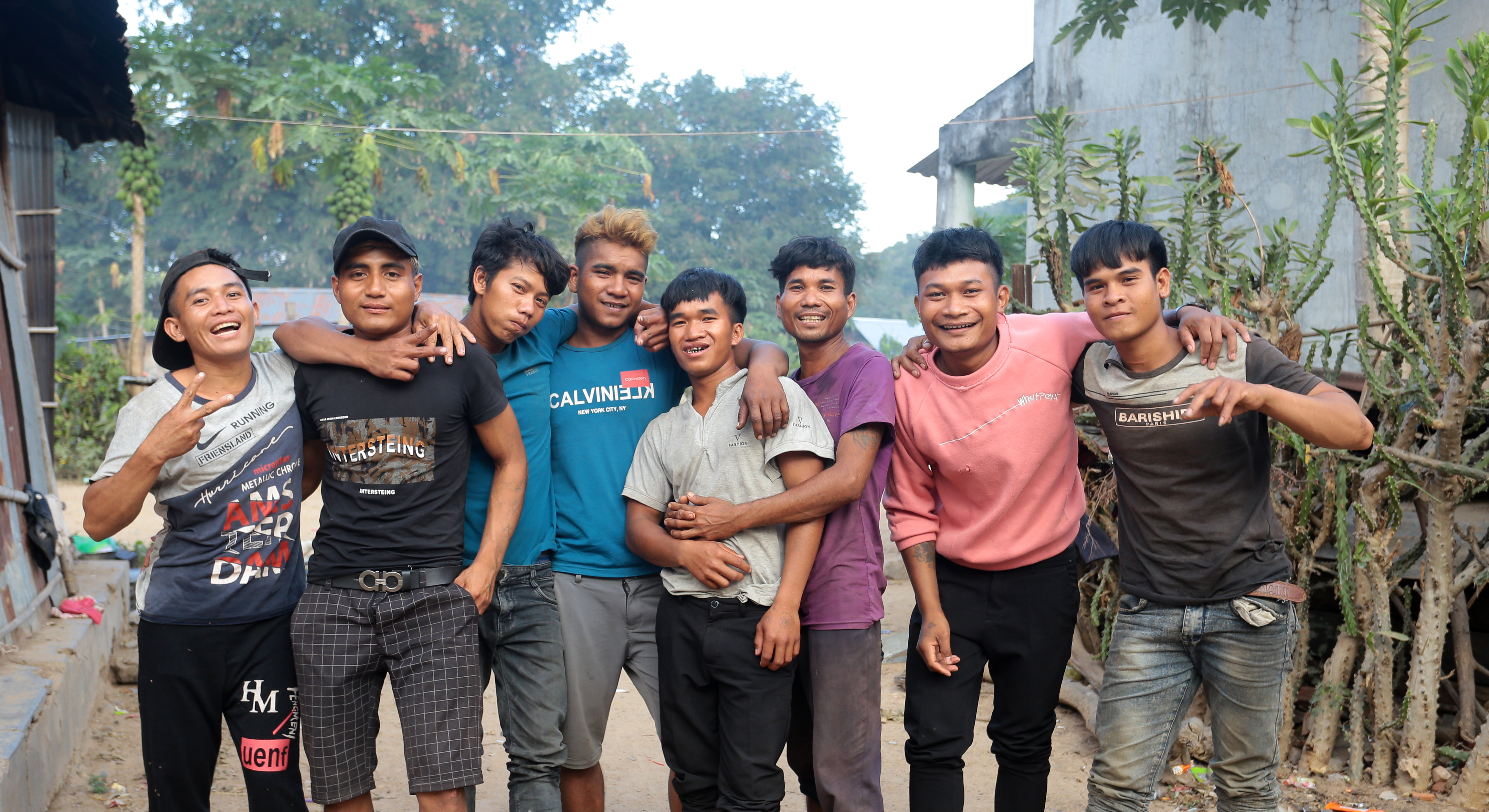 Ray lined up with his friends, all smiling and posing for the camera. Ray is in the middle