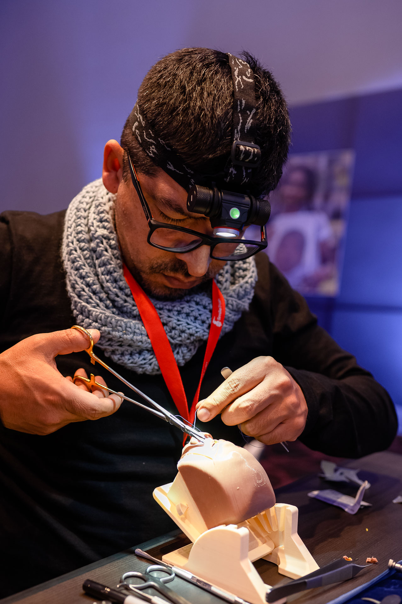 Huáscar Aillón wearing a headlamp sewing medical stitches onto a Simulare Medical simulator