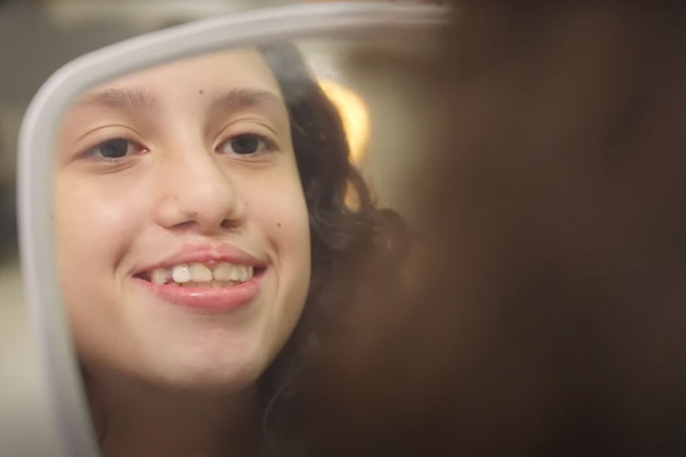 Nasly smiling in a mirror after cleft treatment at Smile Train partner FISULAB in Bogotá, Colombia