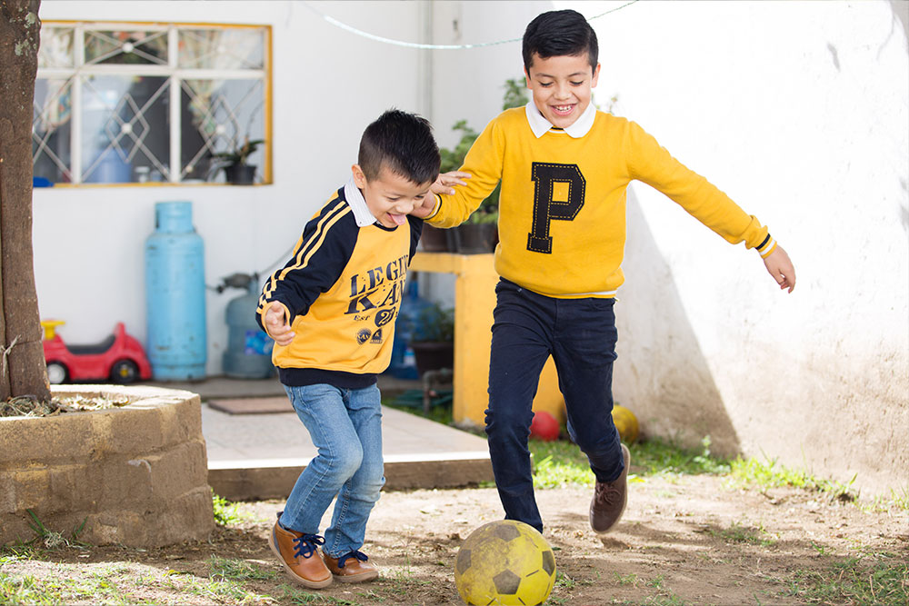 Alex and Carlos kicking a football