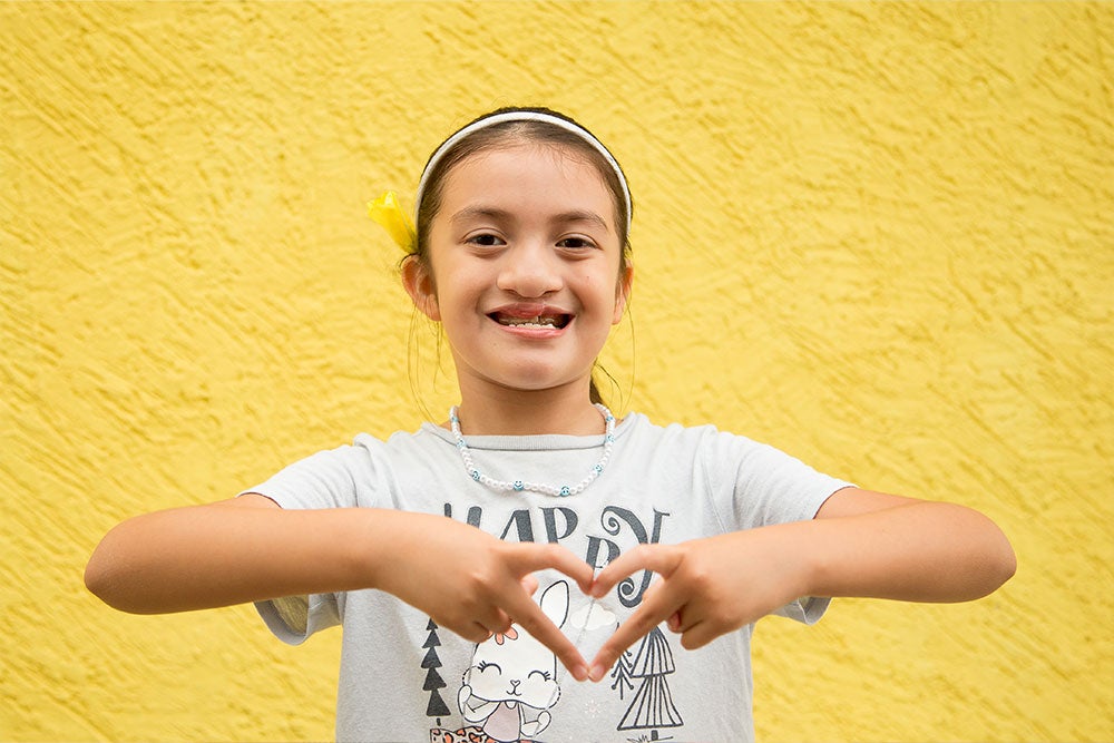 Aquetzaly smiling and making a heart with her fingers