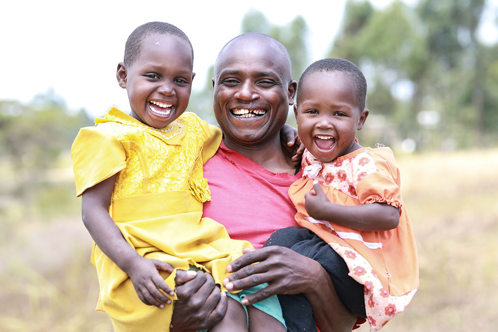 Wesley holding his two daughters, one in each arm