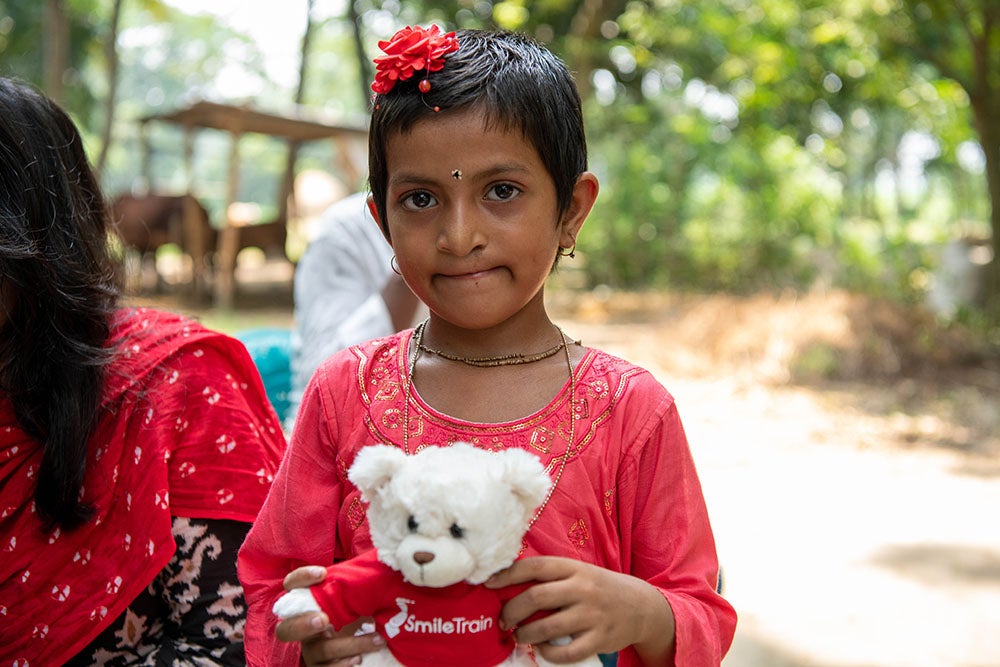 Disha holding a white bear in a red Smile Train shirt