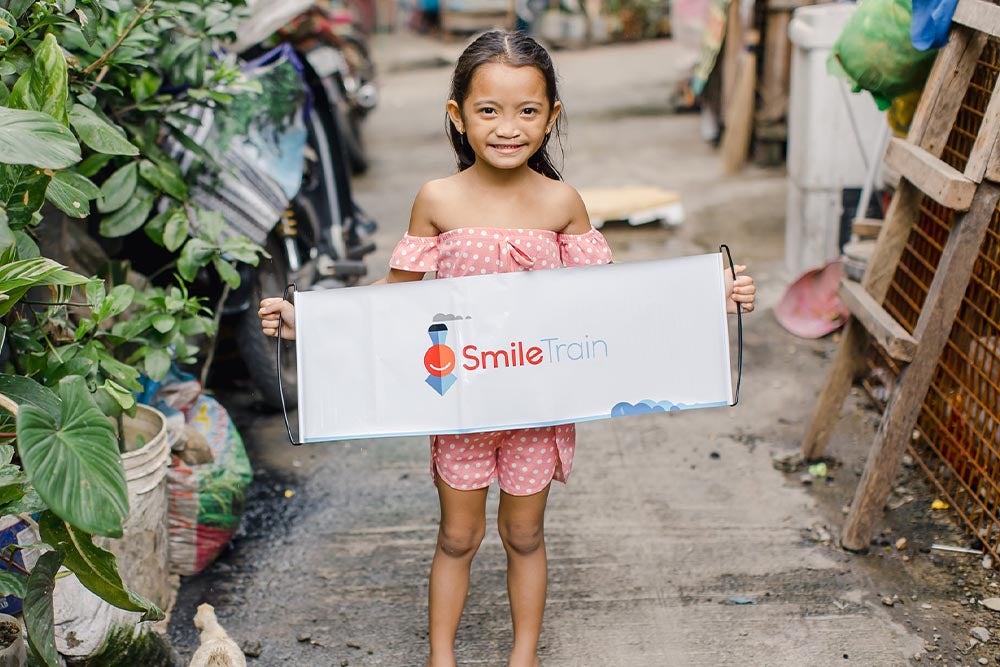 Leana holding a Smile Train banner