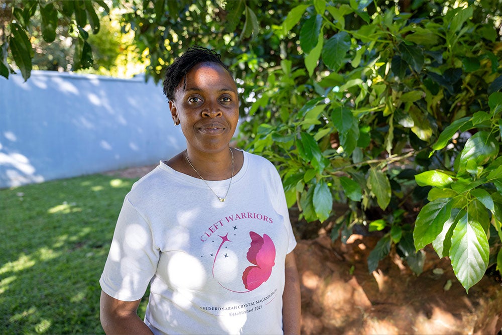 Danai wearing a Shumiro Trust shirt with a butterfly and the words “Cleft Warriors”