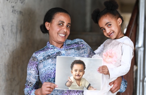 Zinash holding Marsillas and a picture of her before cleft surgery
