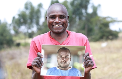 Wesley smiling, holding a picture of himself before cleft surgery