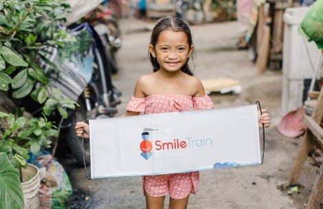Leana holding a Smile Train banner