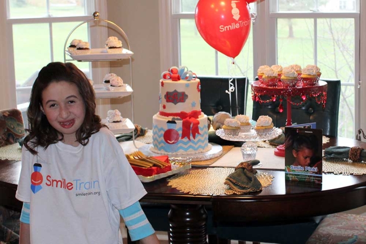 Smile Train supporter in front of cake and balloons 