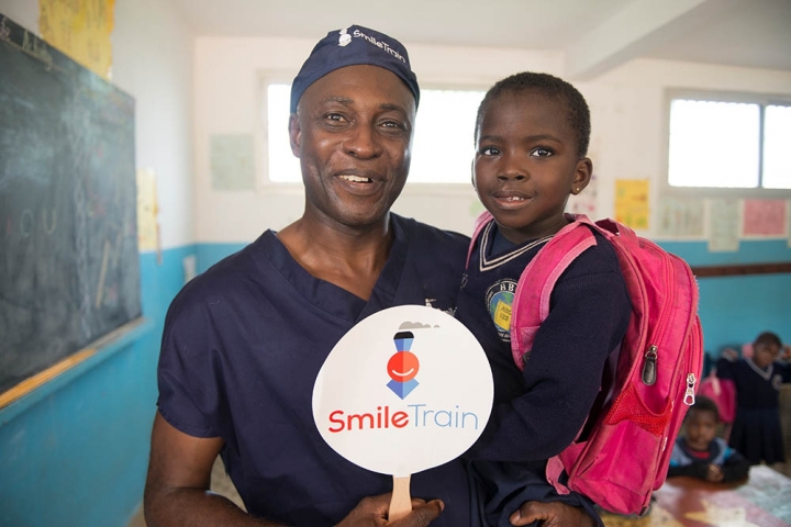 A cleft surgeon holds former patient in his arms