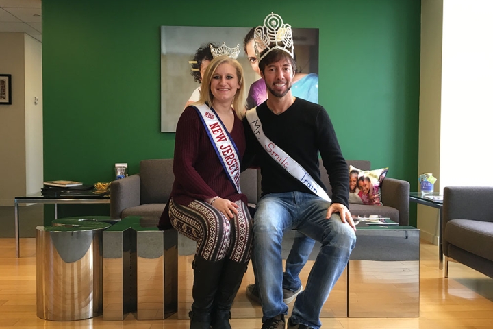 Troy Reinhart wears a crown next to a pageant winner at Smile Train's old offices