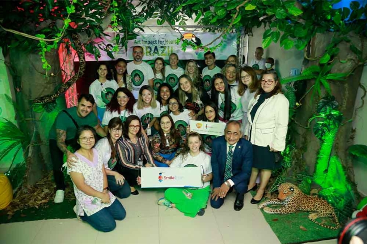 Art Impact Brazil staff and partners smiling and holding Smile Train signs