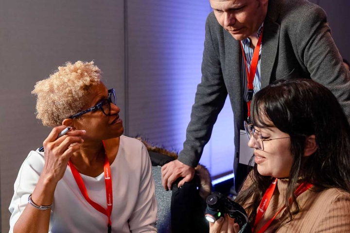 Dr. Judy Ward and another doctor sitting down with a Simulare cleft model on the table. They are talking to Dr. Juan Carlos Zambrano who is standing over them and leaning on their chairs