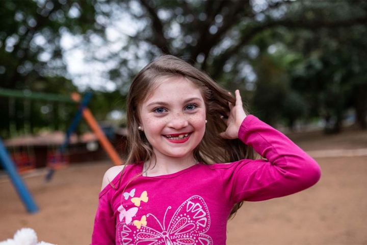 Milena smiling on a playground, tossing her hair back