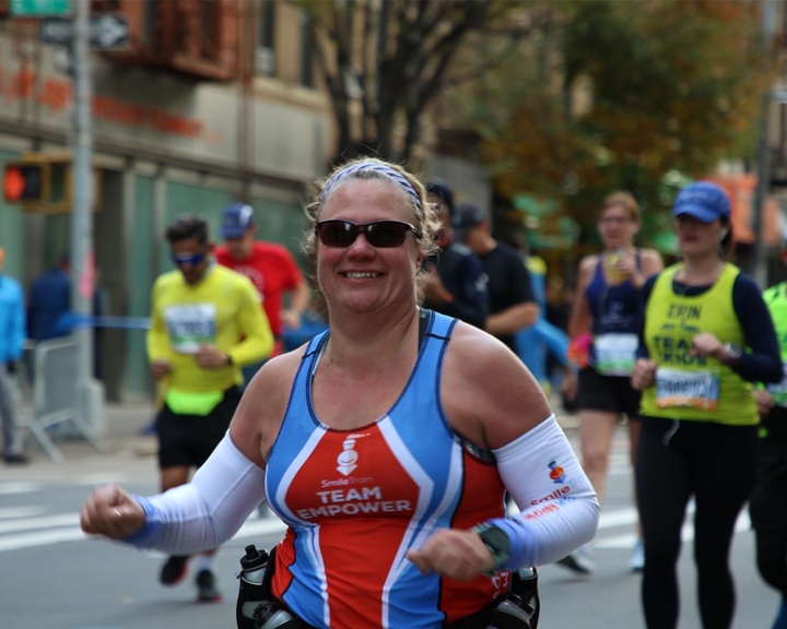 Woman running in marathon with Smile Train kit