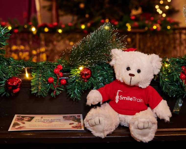 Smile Train teddy bear and flyer in front of a Christmas Tree