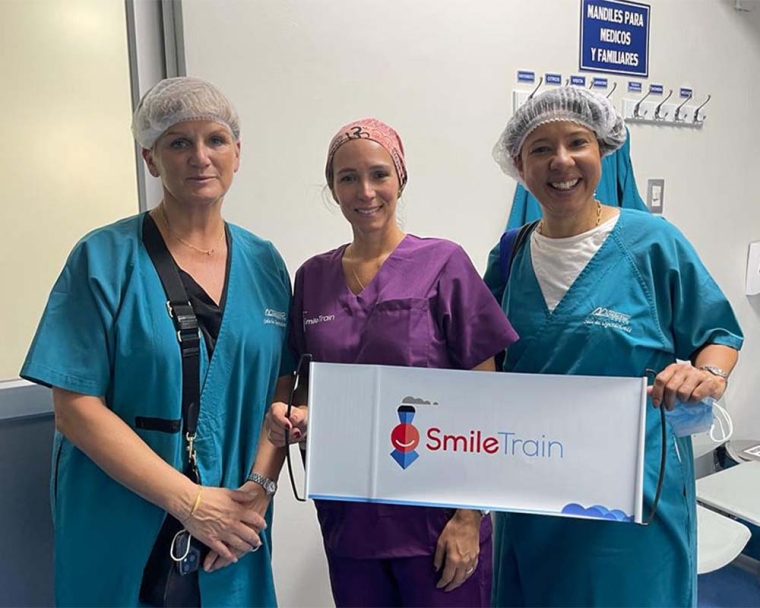 Sue Maughan smiling with Peruvian partners and holding a Smile Train sign