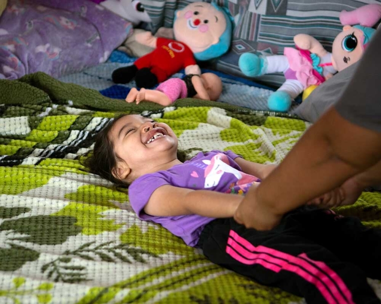 Itzayana smiling and playing on her bed after cleft surgery