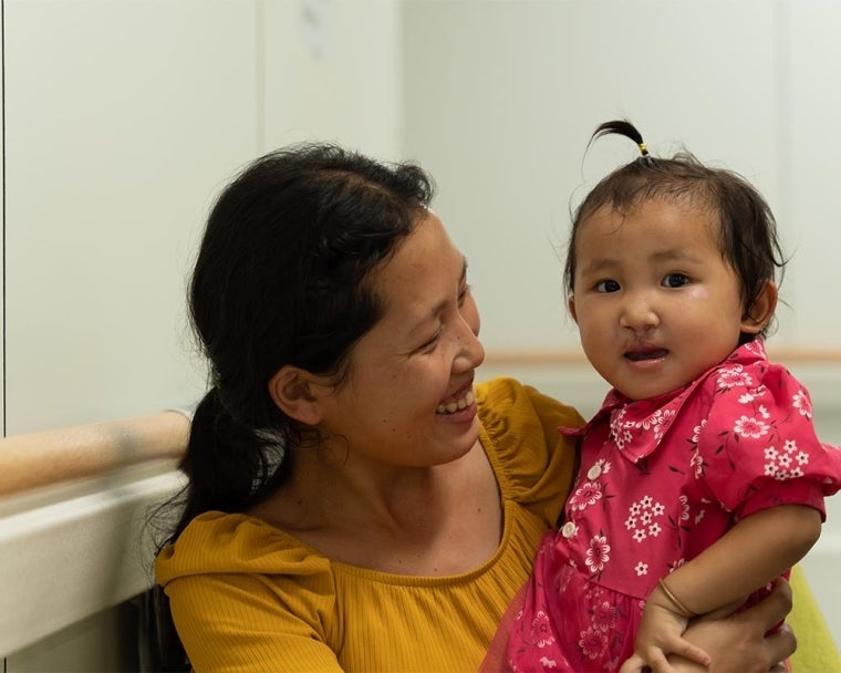 Ming Lao smiling and holding Nalee after her cleft surgery