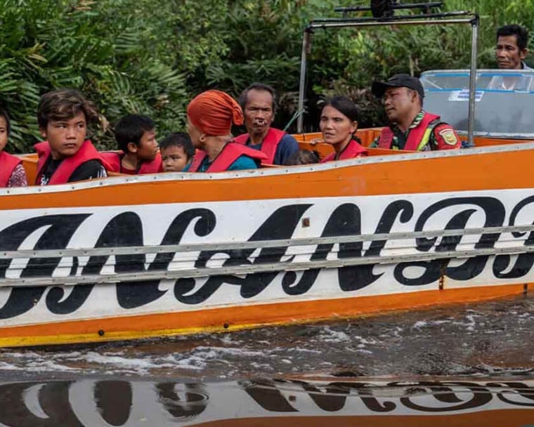 Alim and Rajib riding a boat with their family to the treatment centre before cleft surgery