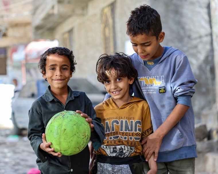 Bilal smiling and holding a football with his brothers after cleft surgery