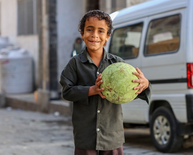 Bilal smiling and holding a football after cleft surgery